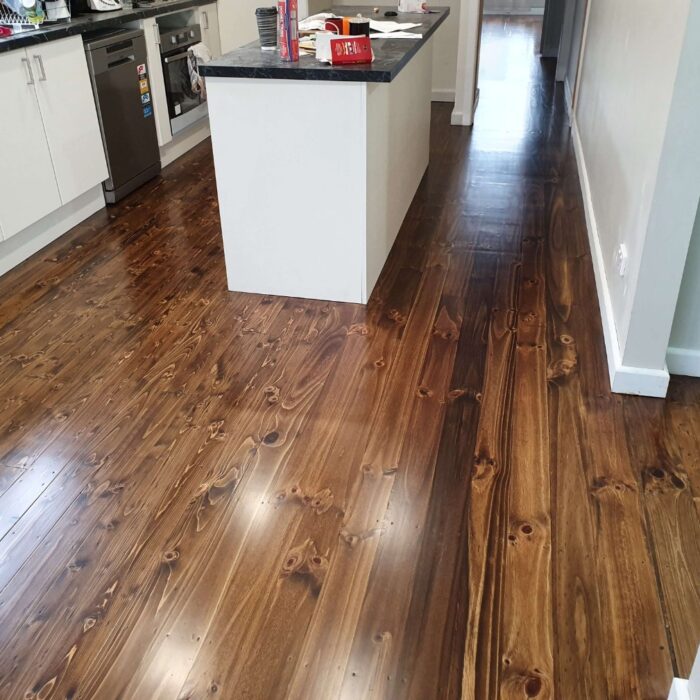 Stained radiata pine floor in a kitchen with black benchtops